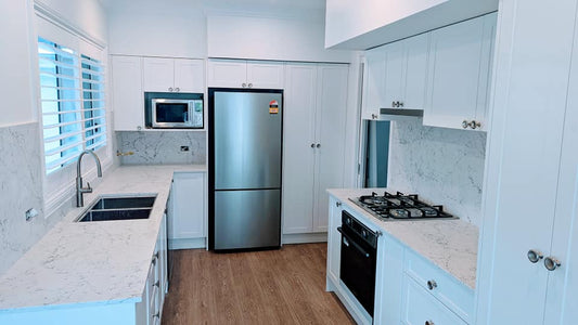 Modern kitchen with engineered stone countertops, stainless steel appliances, and a clean white cabinet design.